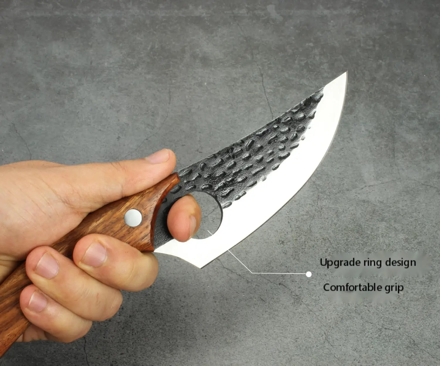 Une main tient un couteau à désosser à lame en acier au carbone à haute teneur martelée et incurvée, avec un manche en bois comportant un design de bague de renfort pour une prise confortable.