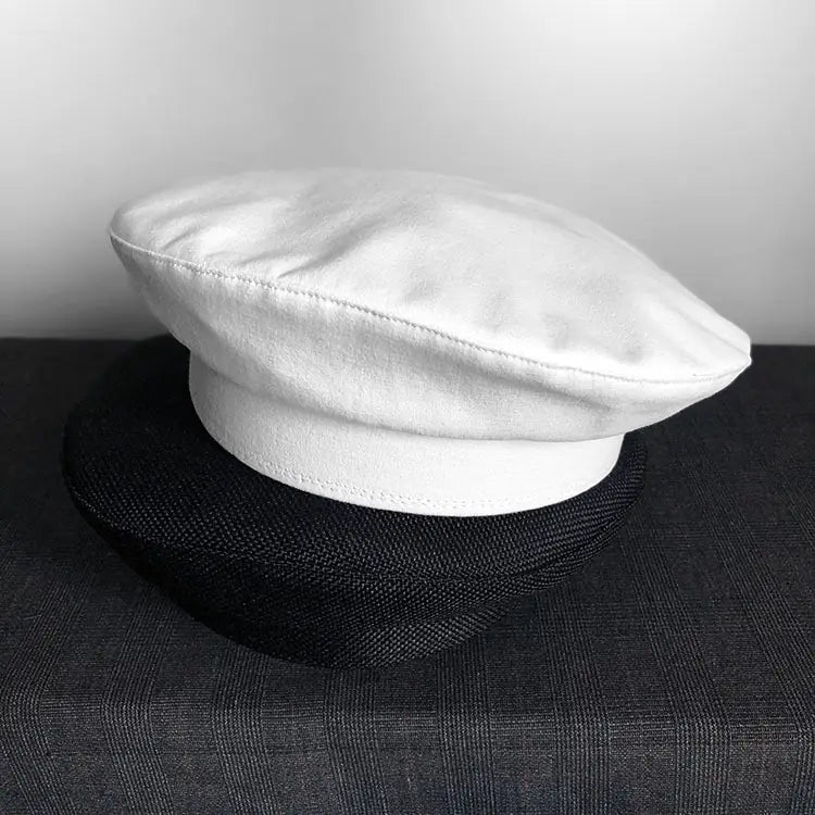 Béret en cuir blanc, avec une calotte lisse légèrement rembourrée et une couture soignée le long de la bordure, présenté dans la collection de béret noir en laine pour peintre pour femmes.