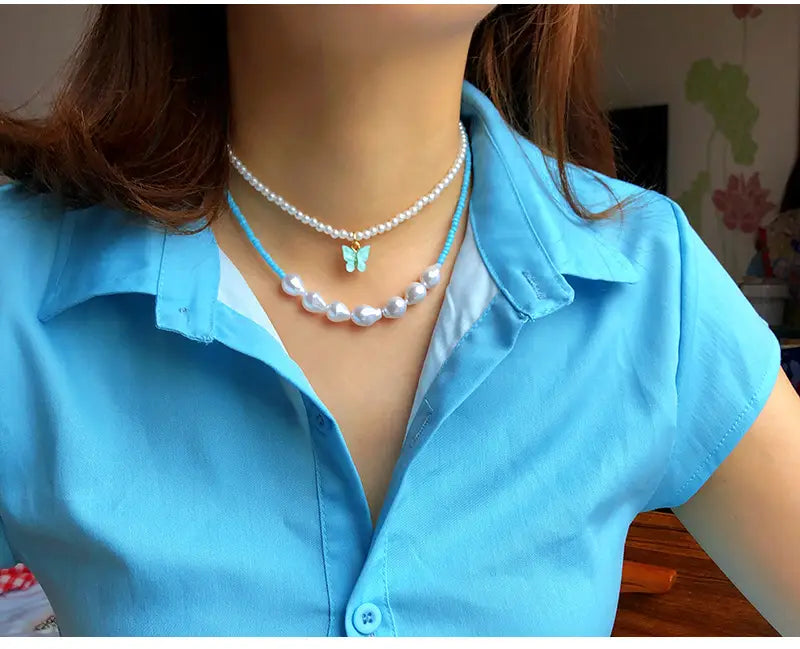 Elegant pearl butterfly charm choker necklace featuring a delicate turquoise cord adorned with a small light blue butterfly charm and white pearls.