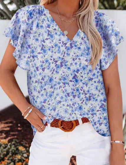 A light blue floral print summer blouse with ruffled flutter sleeves and a v-neckline.