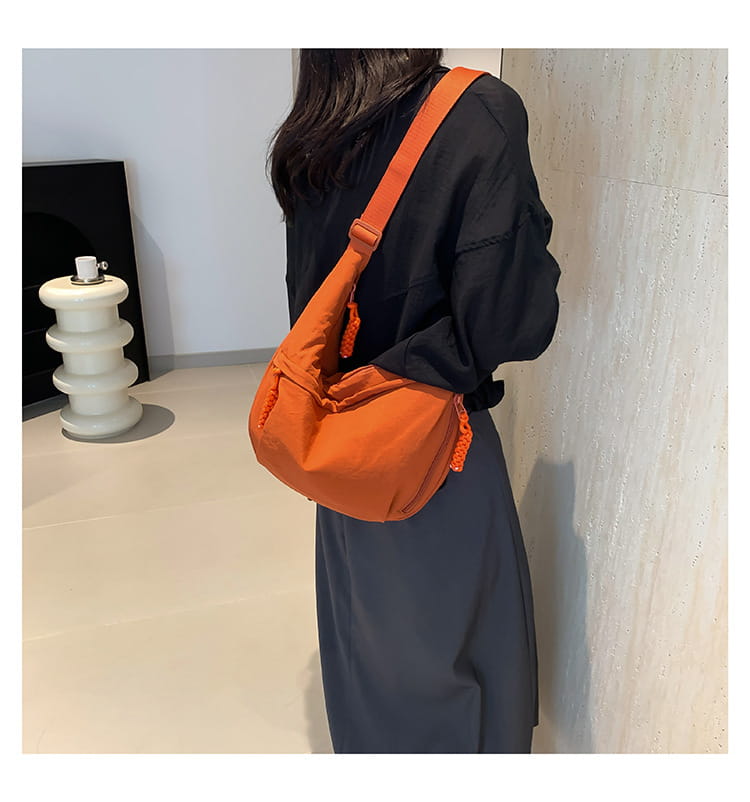 Orange nylon crossbody bag with woven textured fabric body and matching braided strap details designed for large capacity hobo shoulder use.