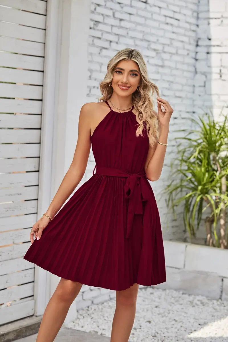 A maroon halter neck pleated chiffon mini dress with a matching belt tied at the waist.