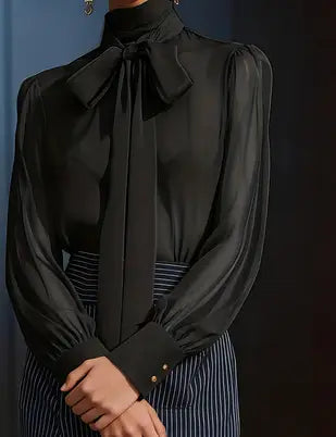 Black satin puff sleeve blouse with a large bow at the neckline and gold buttons on the cuffs.