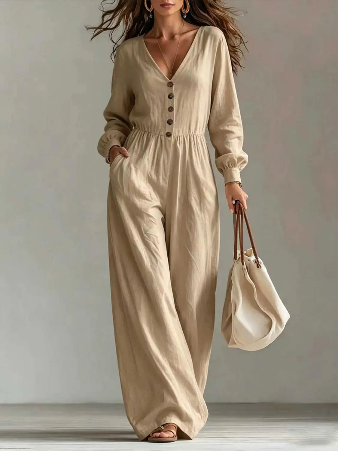 Une combinaison pour femmes en lin beige, décolleté en V, manches longues, fermeture boutonnée à l’avant et design à jambes larges.