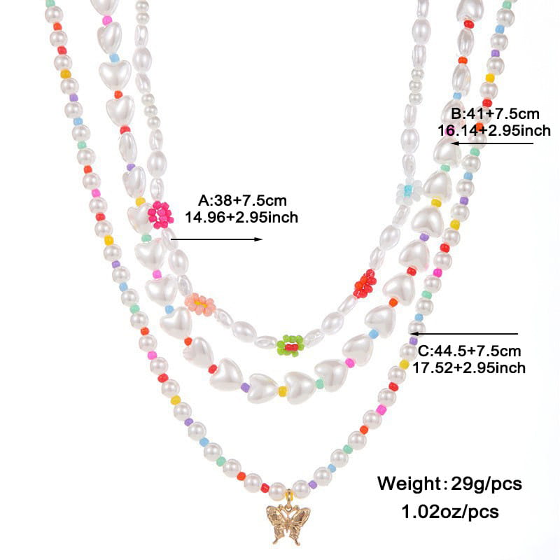 A delicate three-strand necklace featuring white heart-shaped pearls and colorful beads with a gold-toned butterfly pendant in a layered gold butterfly and pearl jewelry set for women.