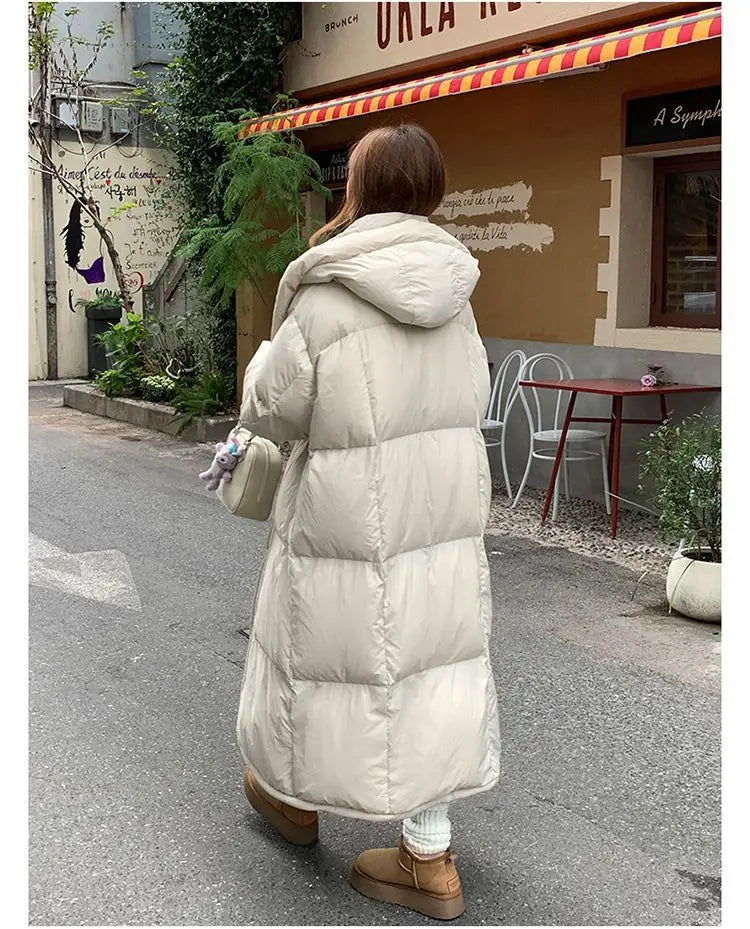 Cream-colored women’s long quilted winter puffer coat with a hood and down insulation for cold weather.