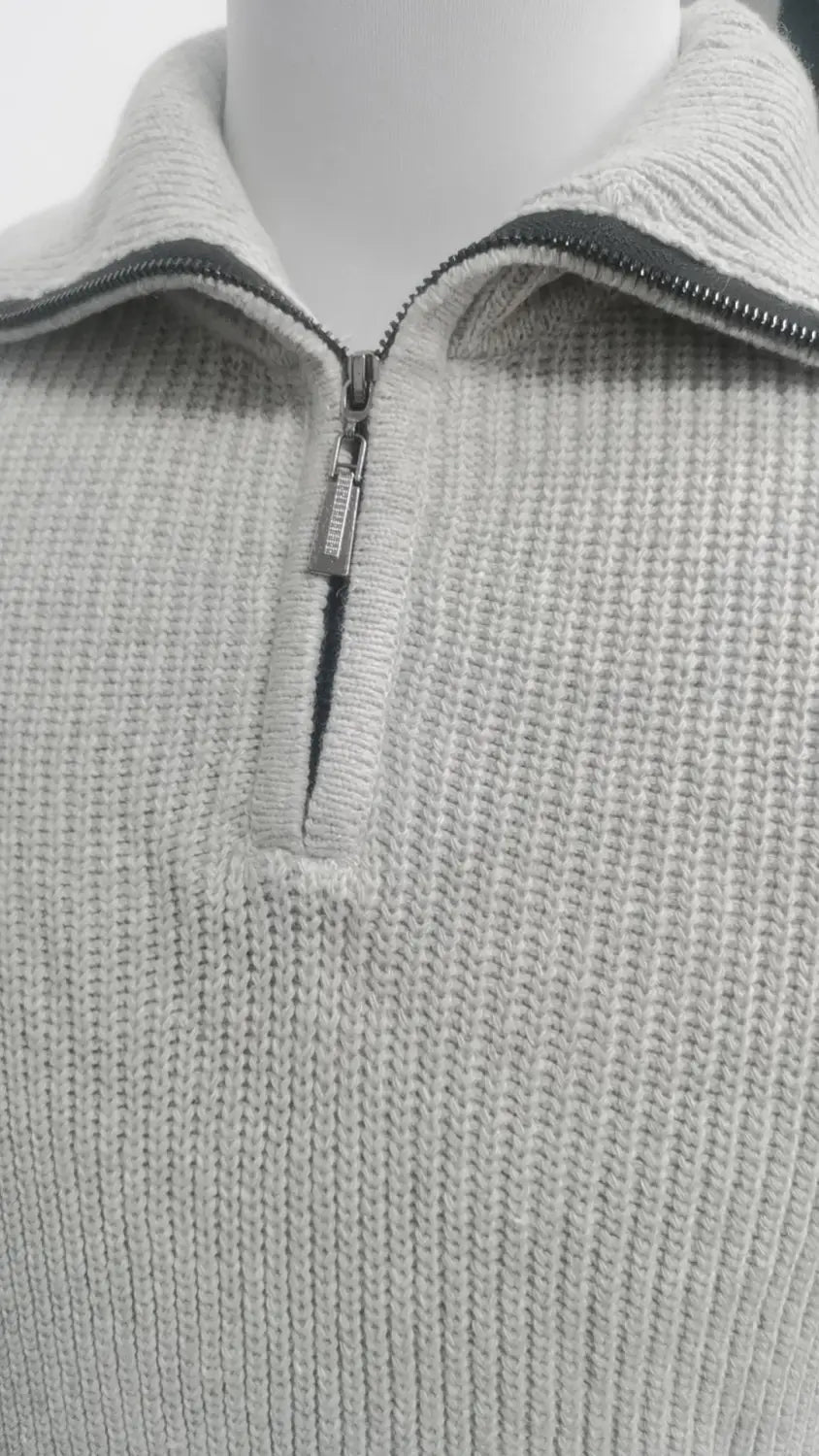 Herren-Halbrollkragenrippstrickpullover aus hellgrauem Strick mit Viertel-Zipp und kontrastierender schwarzer Verarbeitung entlang des Kragens.