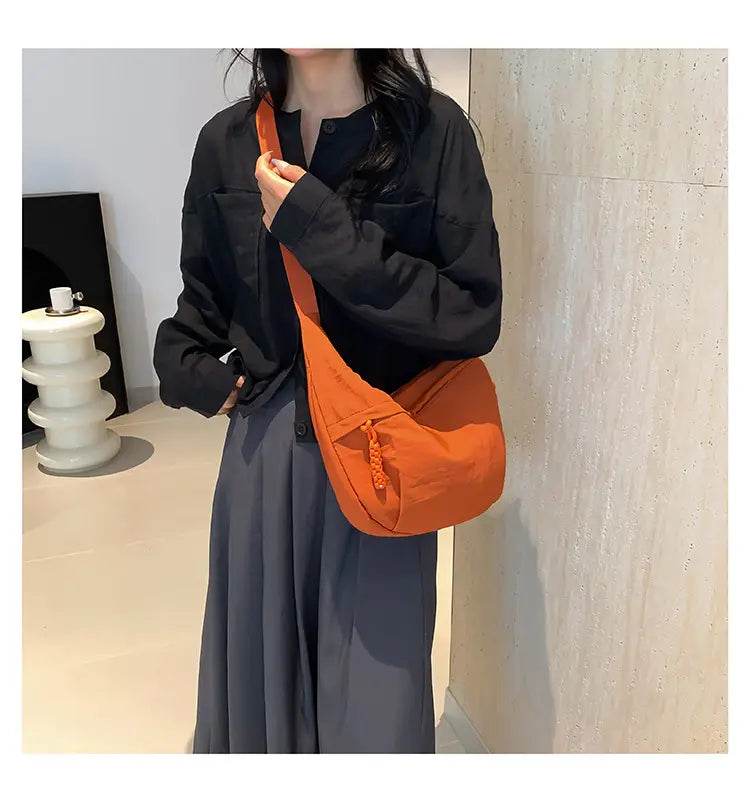 Orange canvas nylon crossbody bag with tassel detail and large capacity hobo shoulder design.
