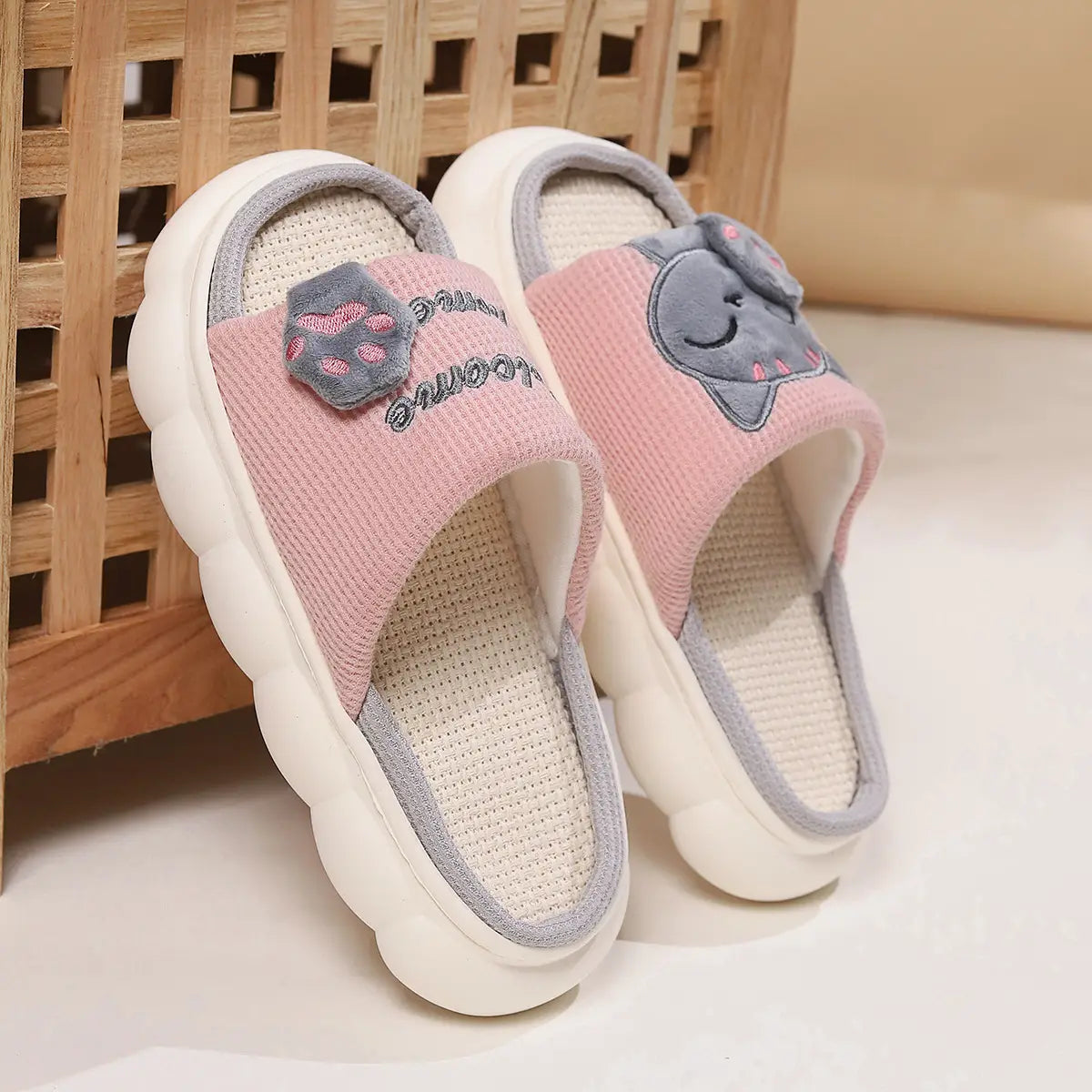 Pink and gray plush cat-themed slide sandals featuring a textured fabric upper with embroidered details and a white cushioned anti slip sole.