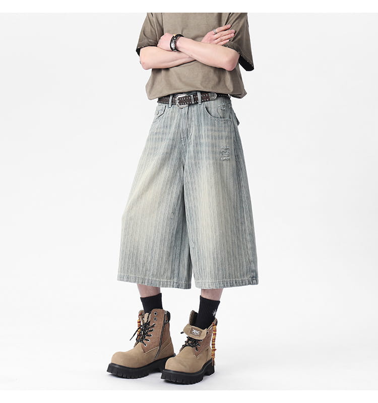 Striped denim capri shorts featuring wide-leg fit in faded light blue and gray vertically striped wash with distressed details.