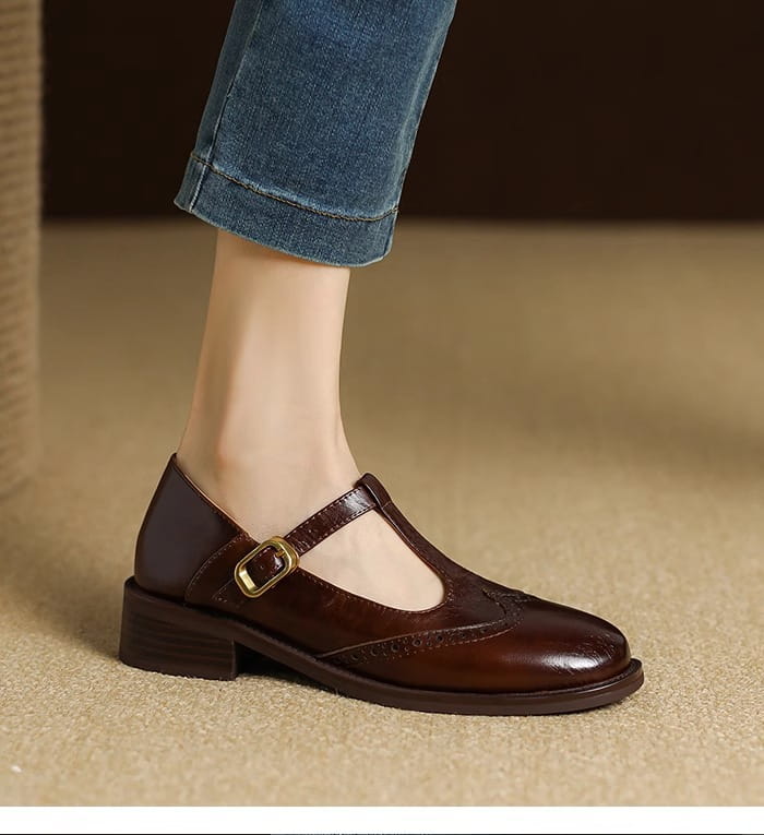 Braune Leder-Brogue-Mary-Jane-Pump mit klobigem Absatz mit T-Riemen und goldfarbenem Schnallenverschluss.