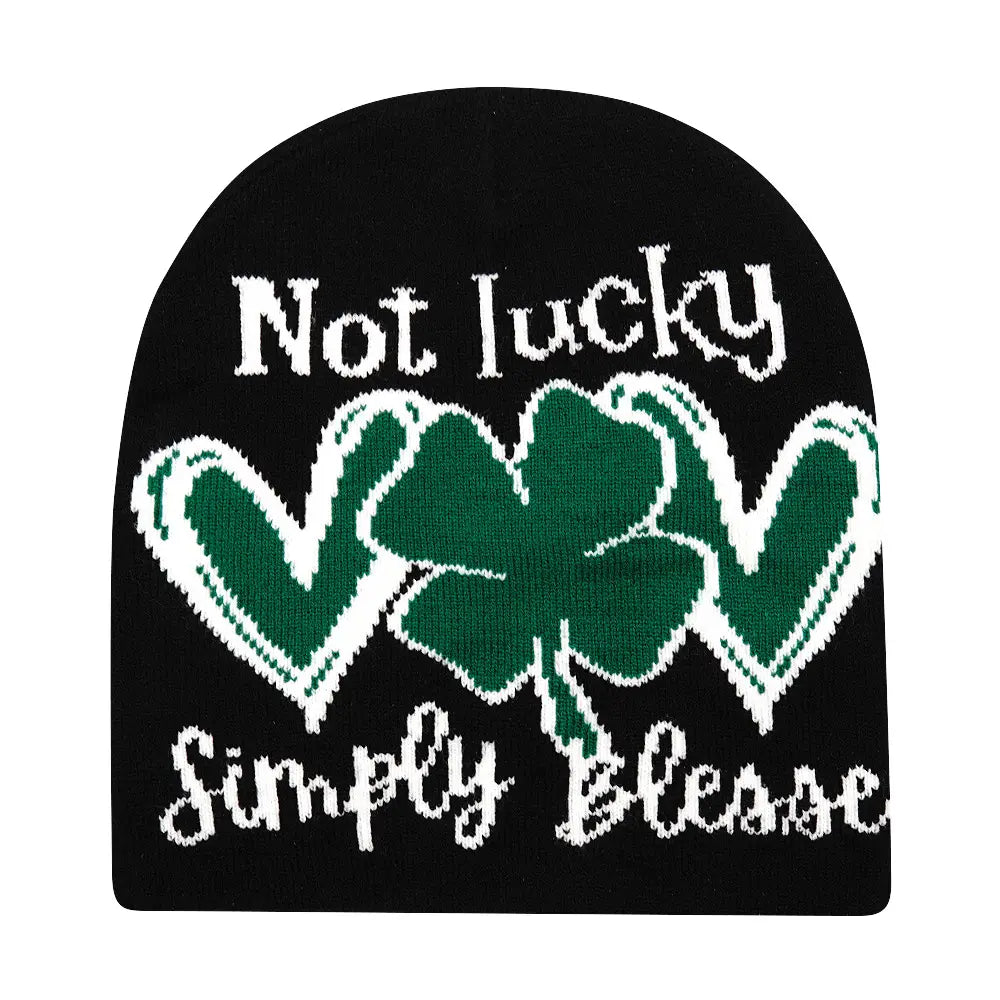 Black knitted beanie winter warm hat featuring a green shamrock and the phrase not lucky simply blessed in white knit lettering.