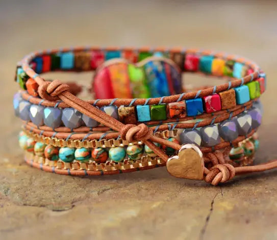A multi-layered leather wrap bracelet featuring colorful turquoise and gemstone beads with a gold-toned heart charm named Rainbow Heart Imperial Stone Leather Wrap Bracelet.