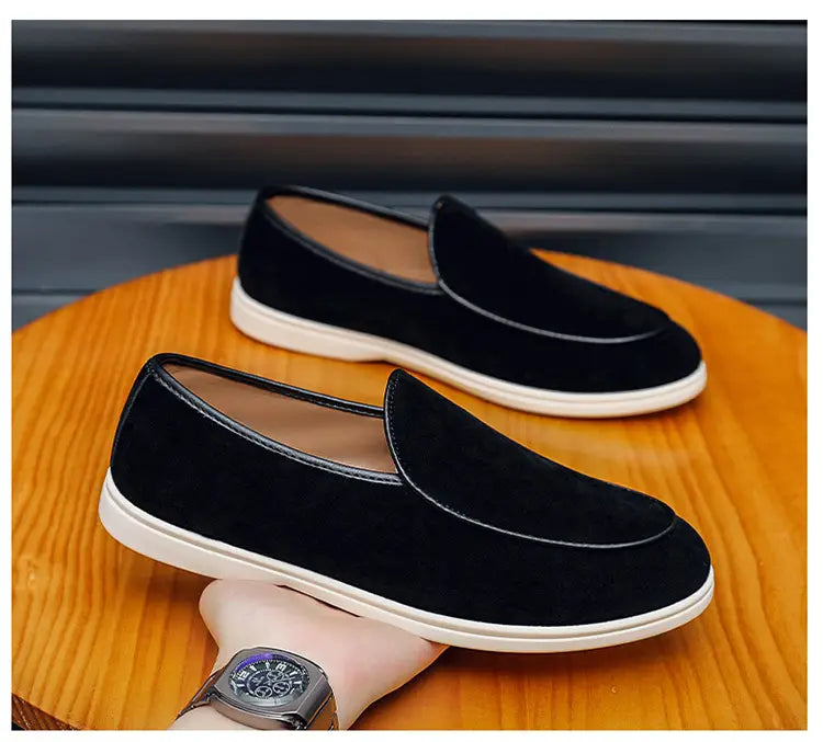 Men’s suede slip on loafers in black with white rubber sole and contrasting black stitching.