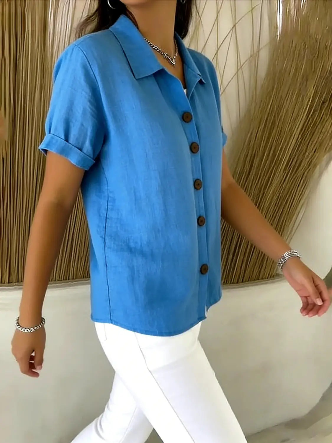 Camisa abotonada de lino para mujer de manga corta en azul vibrante, con cuello clásico y puños enrollados, con botones en marrón oscuro.