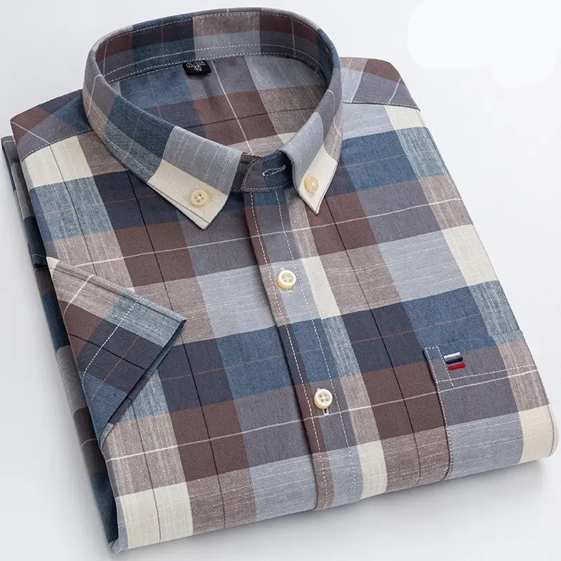 A neatly folded men’s premium 100 percent cotton textured short sleeve button-up shirt with a classic plaid pattern in shades of blue brown and beige and cream-colored buttons.