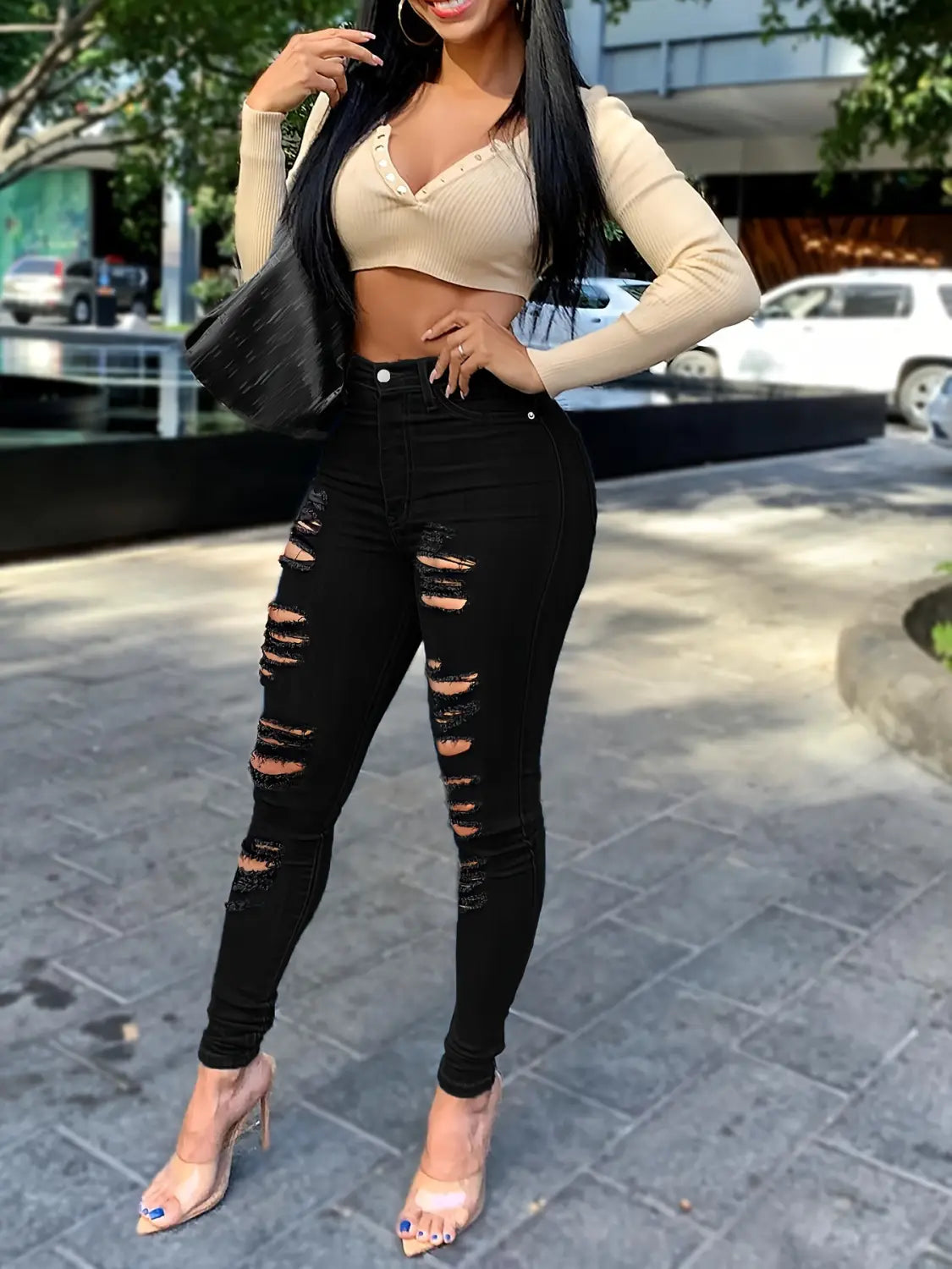 Jeans skinny taille haute échancrés noirs en denim noir avec fermeture à boutons, présenté de face.