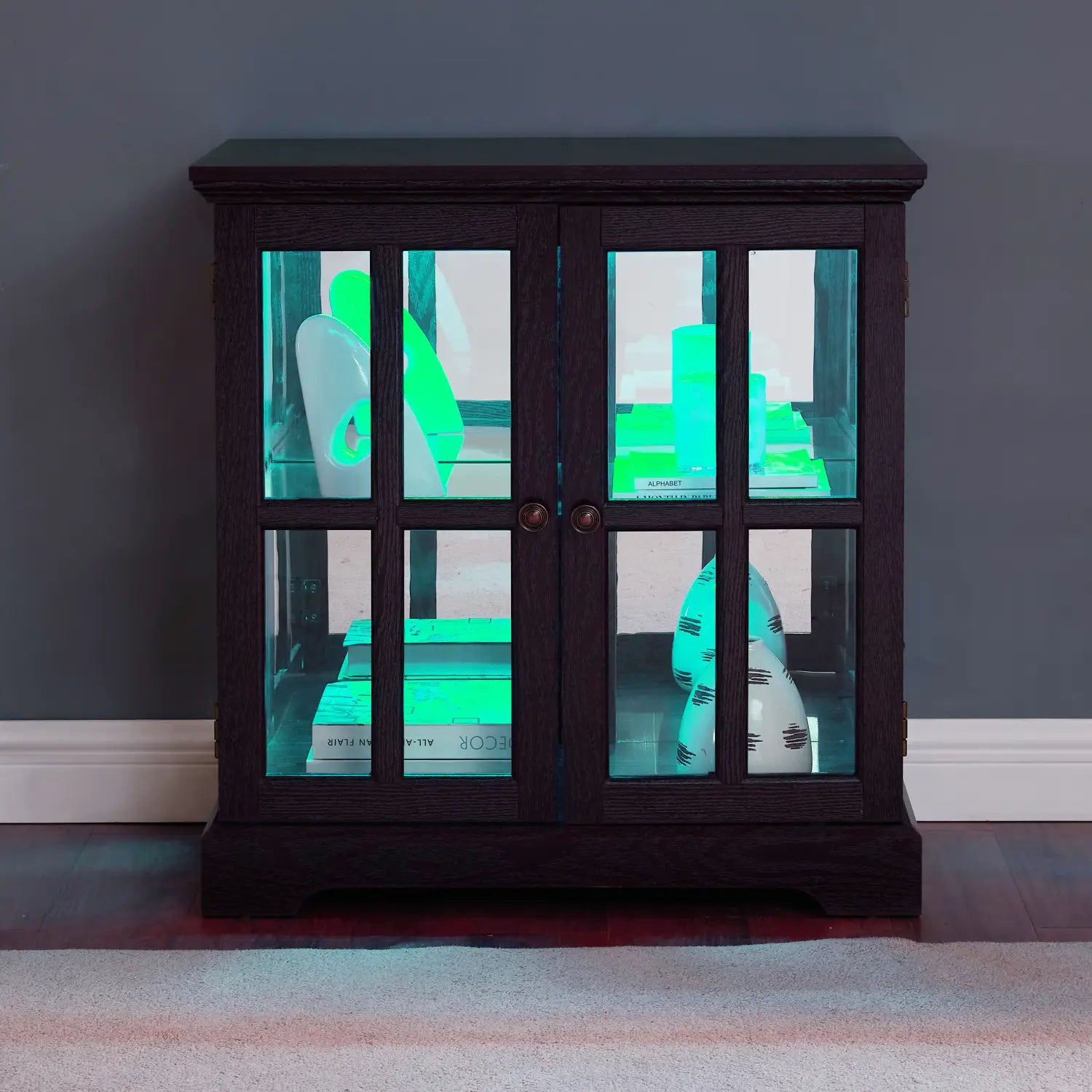 Led curio display cabinet made of dark wood with glass doors and adjustable shelves featuring glowing green interior lighting.