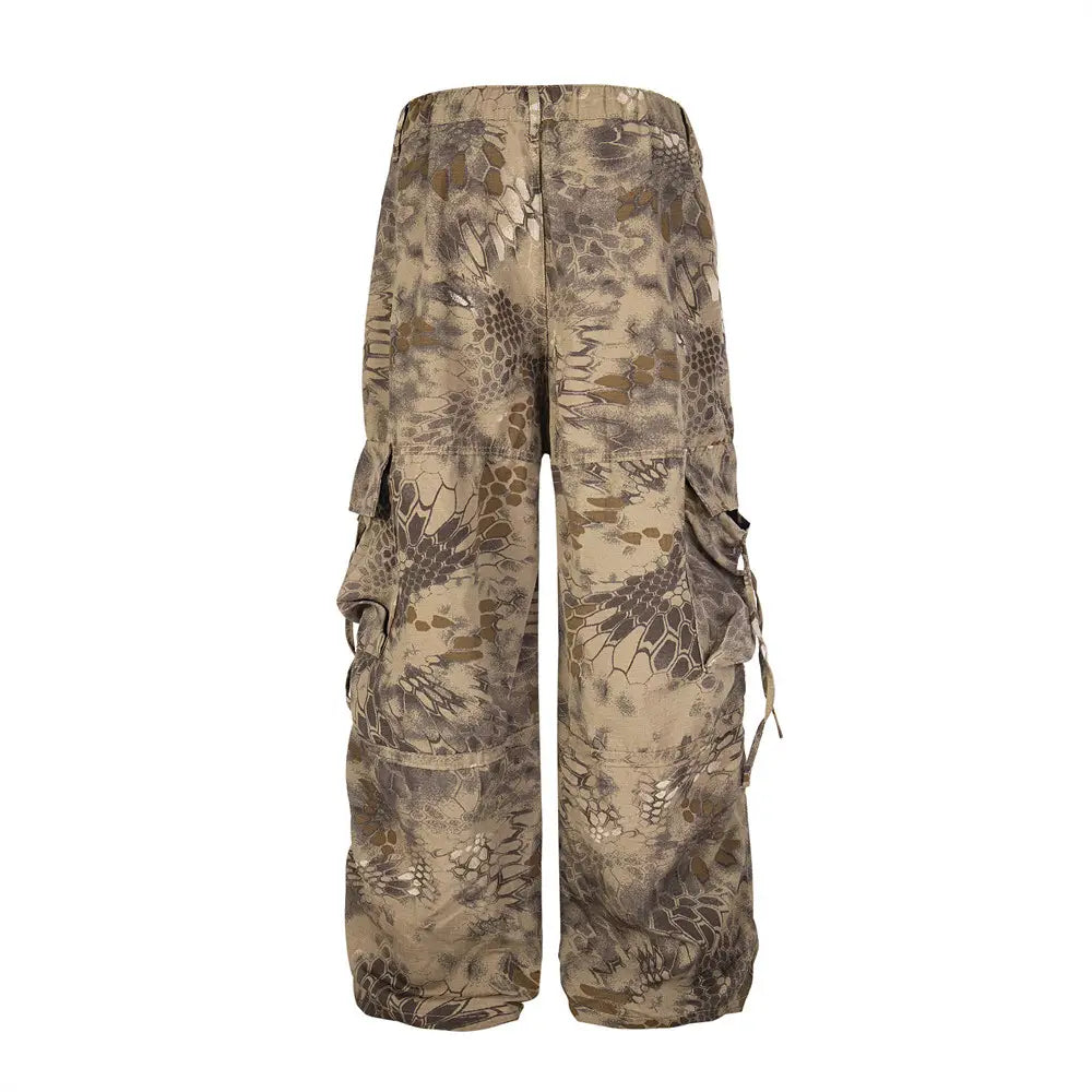 Tan and brown camouflage-patterned wide leg cargo pants with multiple side pockets designed as tactical trousers.