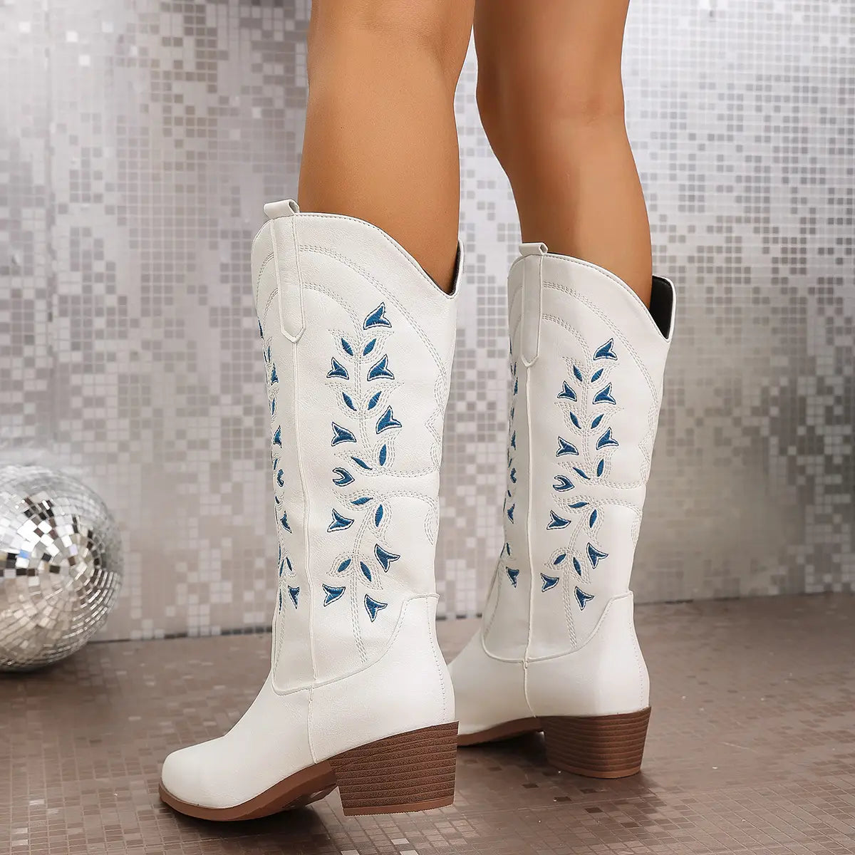 White leather embroidered western cowboy boots featuring blue leaf embroidery and brown chunky block heels with a pointed toe.