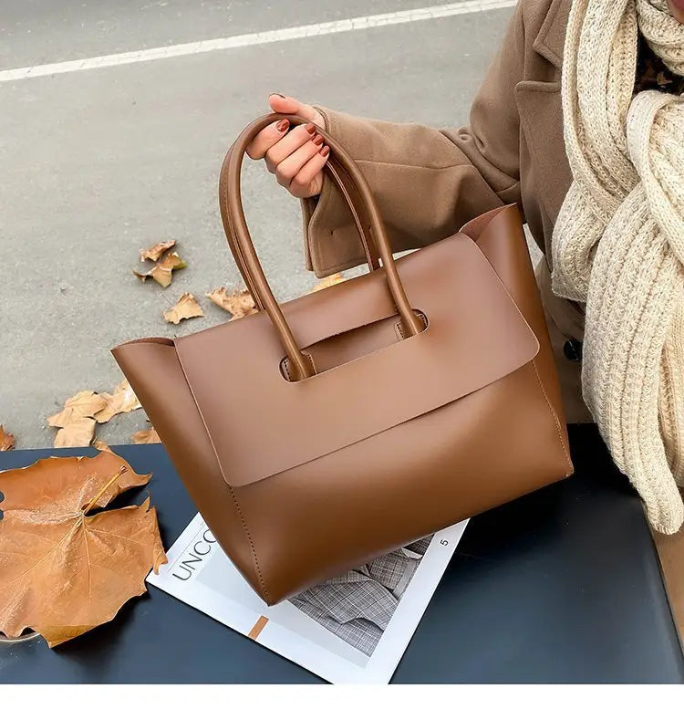 A sleek tan vintage structured leather tote bag with top handles and a minimalist flap closure.