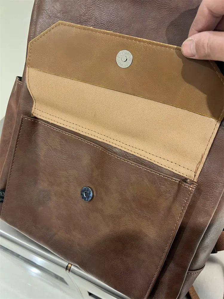 Vintage leather college backpack in brown with tan interior lining and silver toned metal clasps designed for large capacity travel use