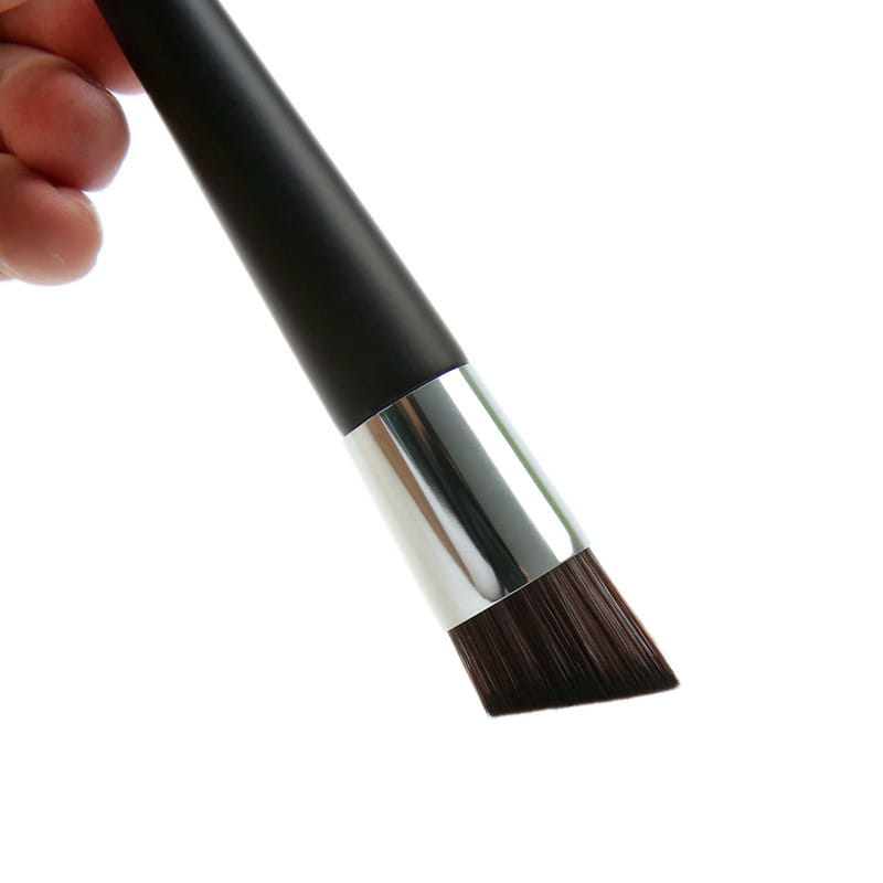 Black-handled foundation brush with a silver ferrule and dense dark brown bristles, featuring a wooden handle and an angled design for makeup application.