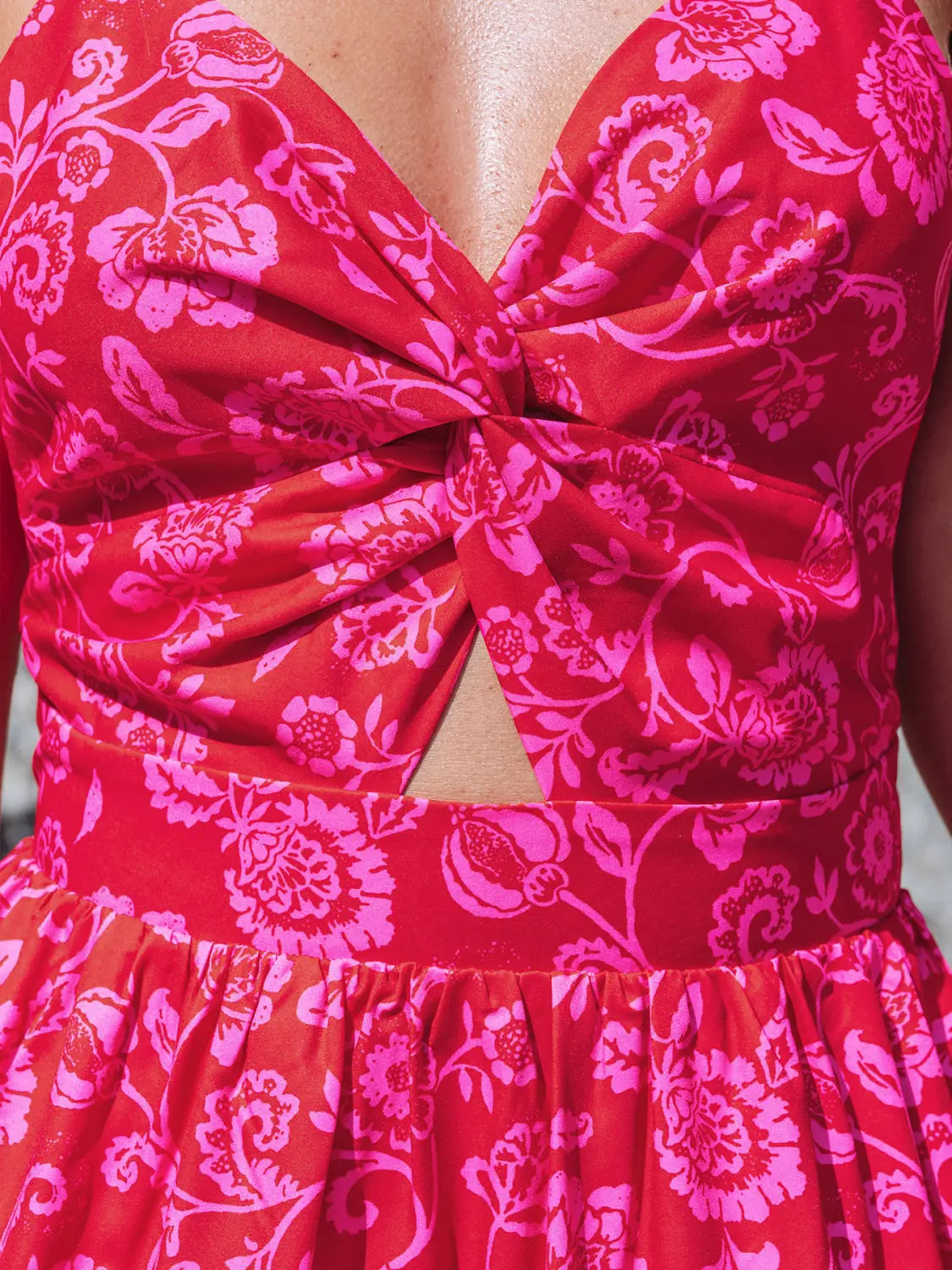 a vibrant red floral knotted v neck spaghetti strap maxi dress with a bold pink floral pattern featuring a ruched bodice and a flattering cutout at the center