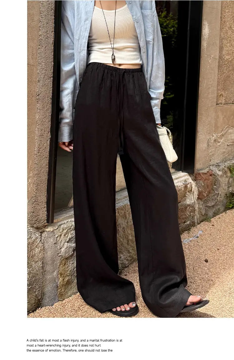Pantalon noir à jambes larges avec une silhouette ample et fluide et une taille élastique, adapté comme alternative au pantalon ample en lin blanc à jambes larges
