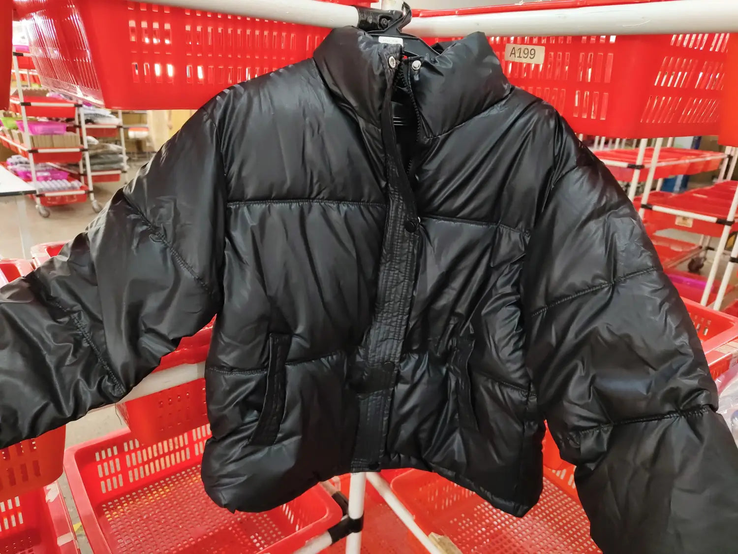 Women’s quilted puffer jacket in black with a shiny quilted exterior and a high collar designed for warmth and style.
