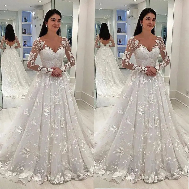 Une robe de mariée blanche en dentelle avec des manches longues et transparentes et des appliqués floraux conçue pour une tenue de mariage.