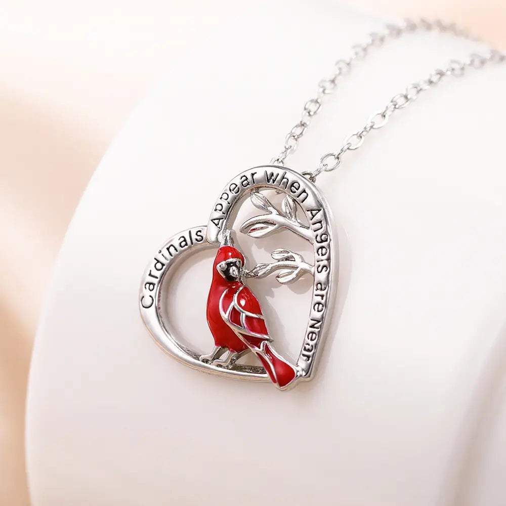 Silver cardinal heart engraved pendant necklace with a vibrant red cardinal perched on a silver engraved branch and the inscription cardinals appear when angels are near along the curve.