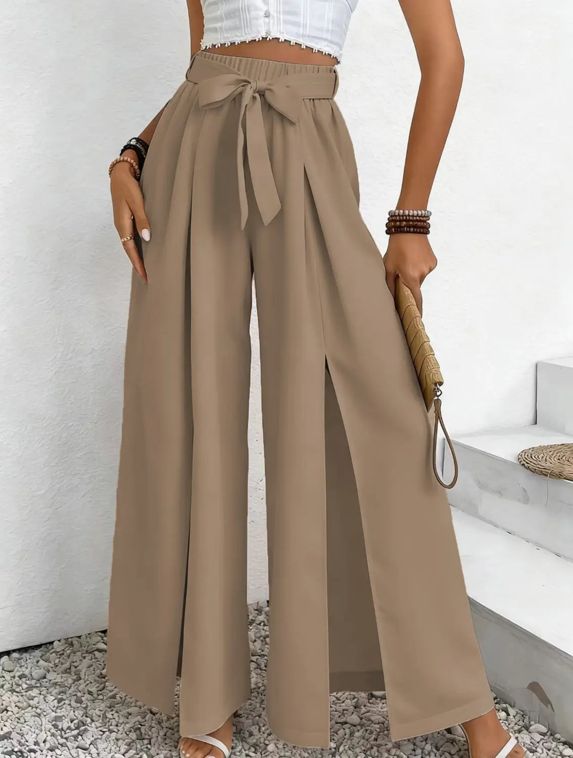 Pantalon ample décontracté à taille haute beige, avec ceinture nouée et fente avant.