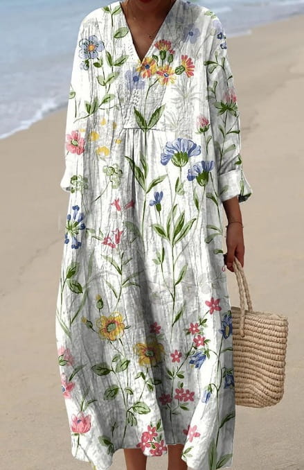 Women’s abstract v neck patterned maxi dress in flowing white fabric with three-quarter sleeves and a floral print featuring delicate pink blue yellow and green blossoms.