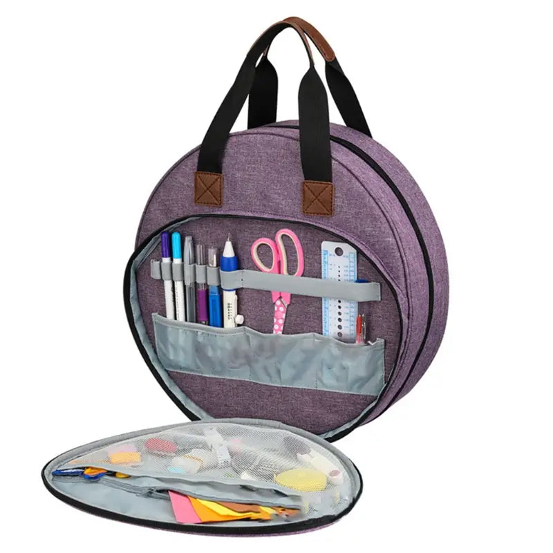 Premium circular embroidery and craft tool storage tote in purple with black handles and brown leather accents featuring organized compartments holding pens scissors rulers and colorful crafting supplies.