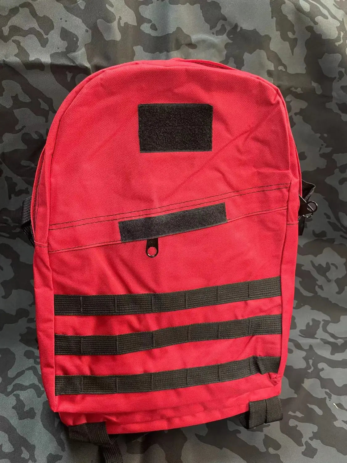 Red tactical camouflage mountaineering backpack with black webbing straps and velcro patches designed for hiking.