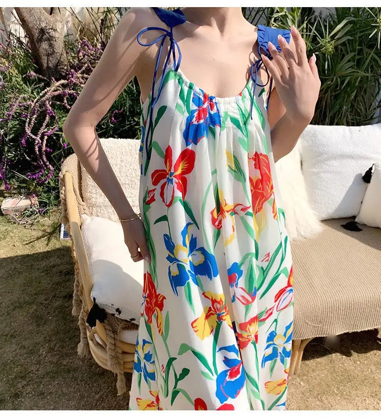 A floral mesh maxi dress with a retro slip silhouette featuring a vibrant floral print of colorful irises and tulips on a white base with adjustable blue tie straps.