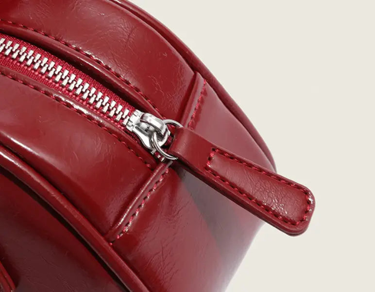 A glossy red leather zipper with silver-toned metal pull tab and matching stitching on a retro glossy PU leather small square handbag 20cm.