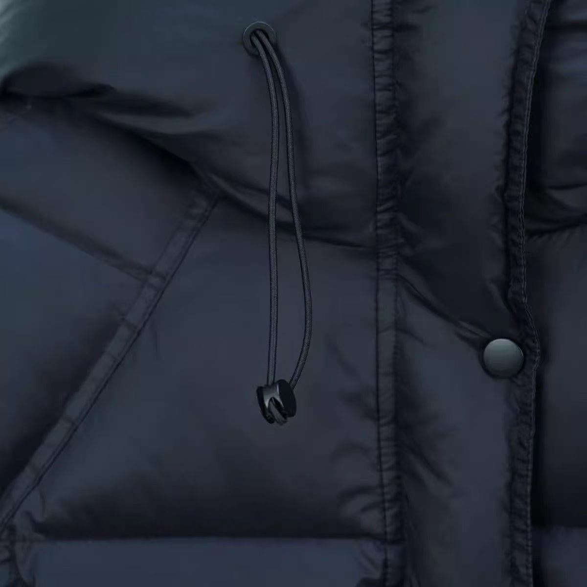 Chaqueta acolchada de plumón color gris oscuro con capucha con cordón y botón con tono plateado, incluida en la colección de chaquetas de invierno acolchadas de plumón moradas para mujer.