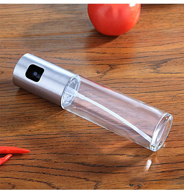 Klare Glas-Ölsprühflasche zum Kochen mit auslaufsicherem Design, mit einer schlanken silbernen Metallspritze und schwarzem Auslöser.