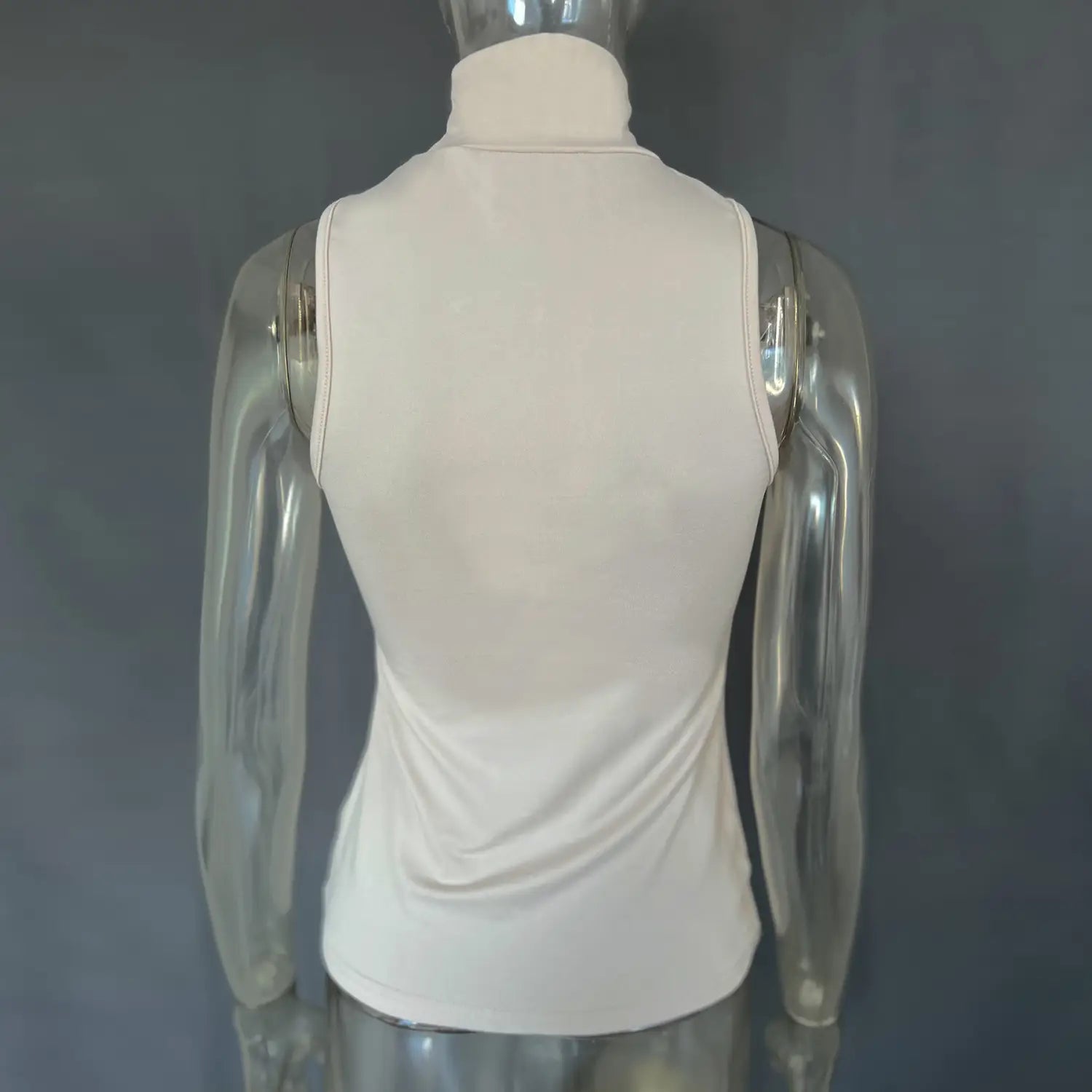Cream-colored form-fitting sleeveless turtleneck gold ring halter stretch top displayed on a mannequin.