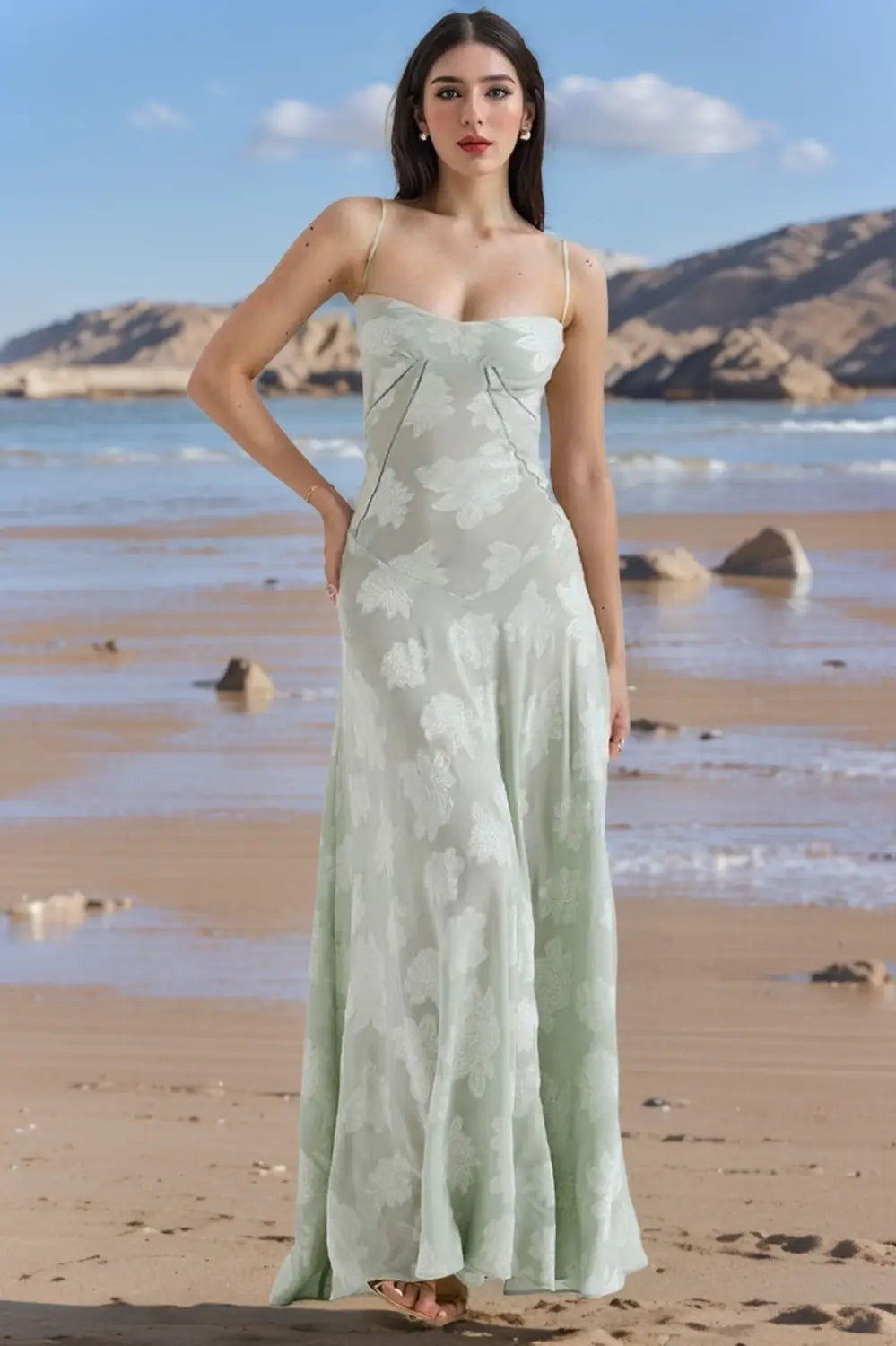 Une robe de soirée maxi vert menthe, fluide, avec un motif floral subtil, de délicates bretelles spaghetti et un design sans dos en dentelle.
