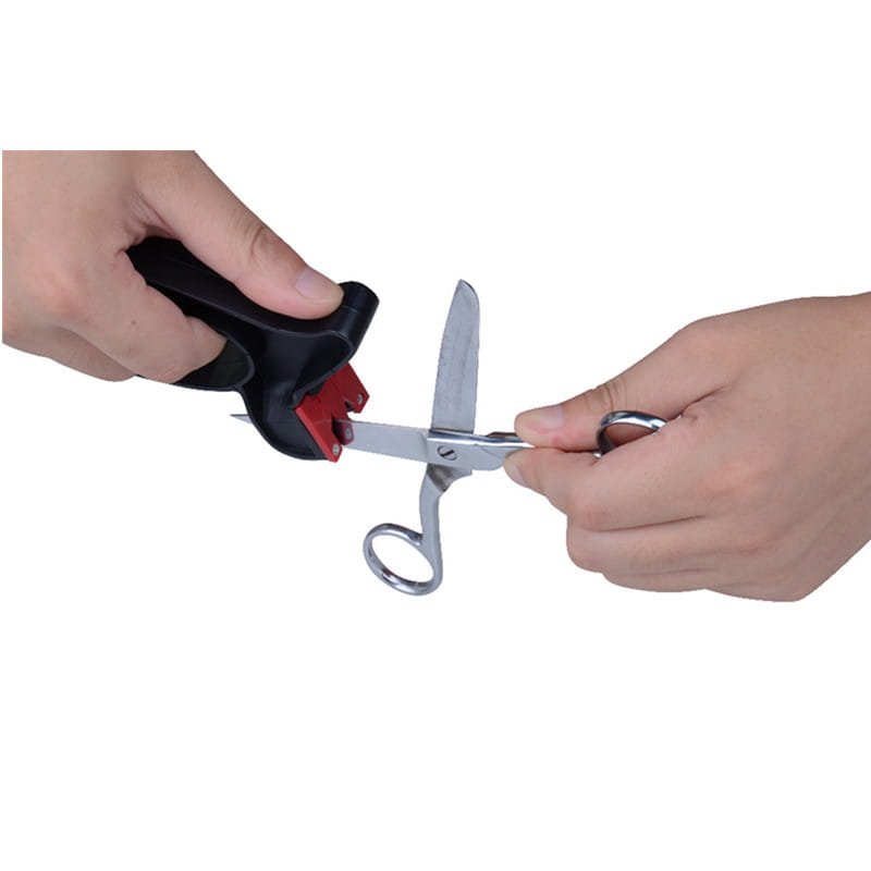 Black and red handheld scissor sharpener made of durable materials sharpening a pair of silver metal scissors for kitchen tool use.