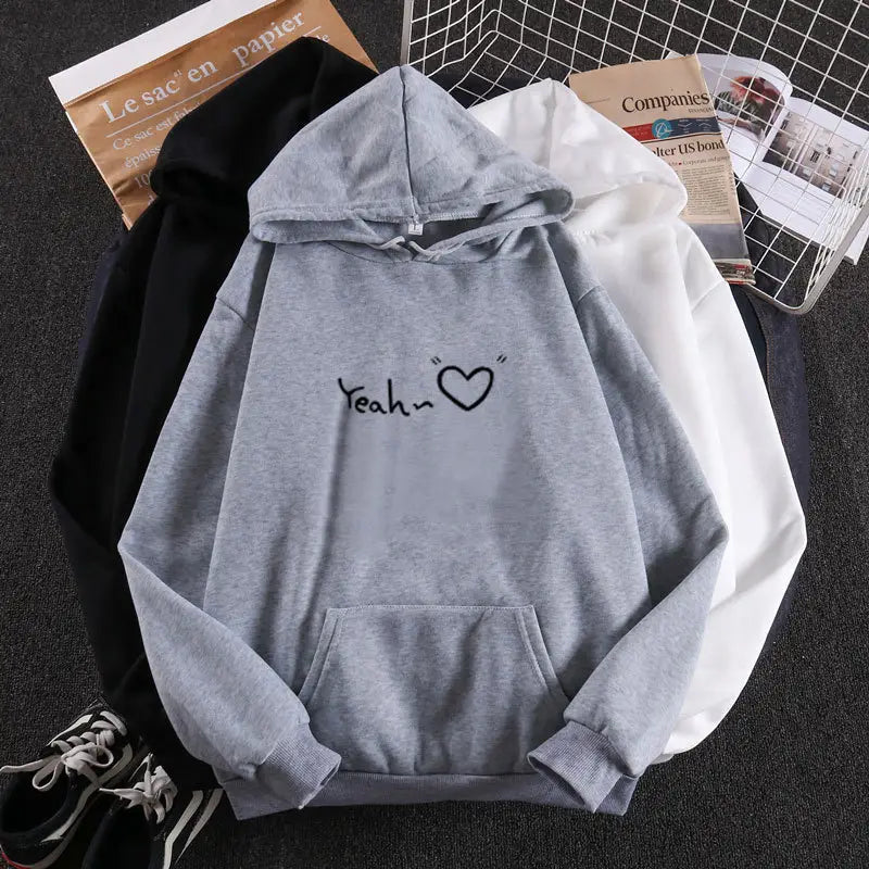 Sudadera con capucha aislada y forro polar de color gris jaspeado, con el corazón 'yeah' impreso en negro en estilo caligrafía cursiva en el pecho.