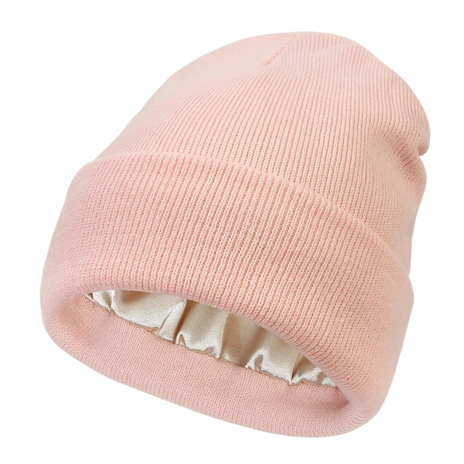 A soft pink ribbed knit beanie with a satin-lined interior designed as a warm winter hat.