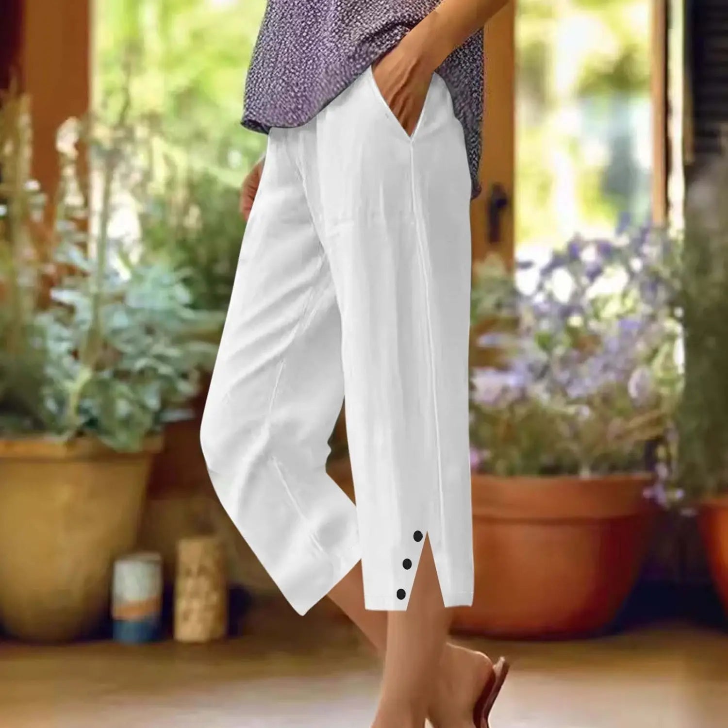 Pantalons capri amples en coton blanc pour femmes avec poches, présentant des accents de boutons noirs au niveau des revers