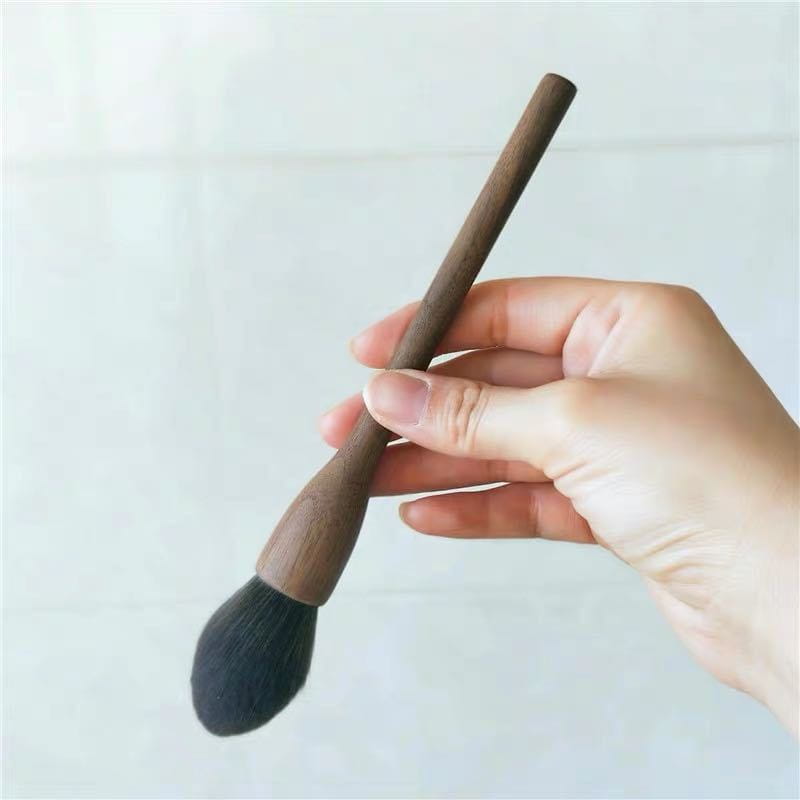 A sleek dark brown wooden-handled makeup brush with soft black fiber bristles from the walnut wood makeup brush set.