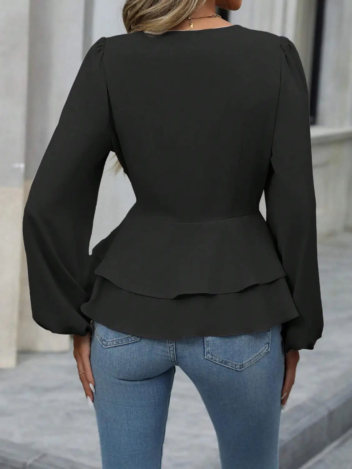 Chaqueta blazer tipo peplum negra con cuello en V, mangas farol largas y cintura entallada.