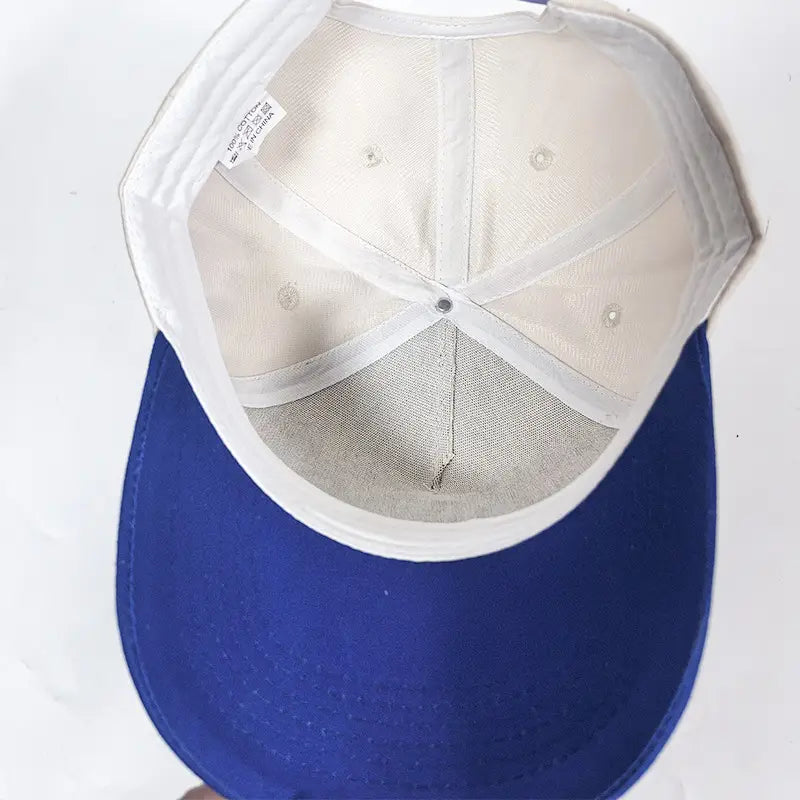 Blue baseball cap with white mesh interior and adjustable strap designed for sun protection featuring the Haitian flag motif in cream blue.