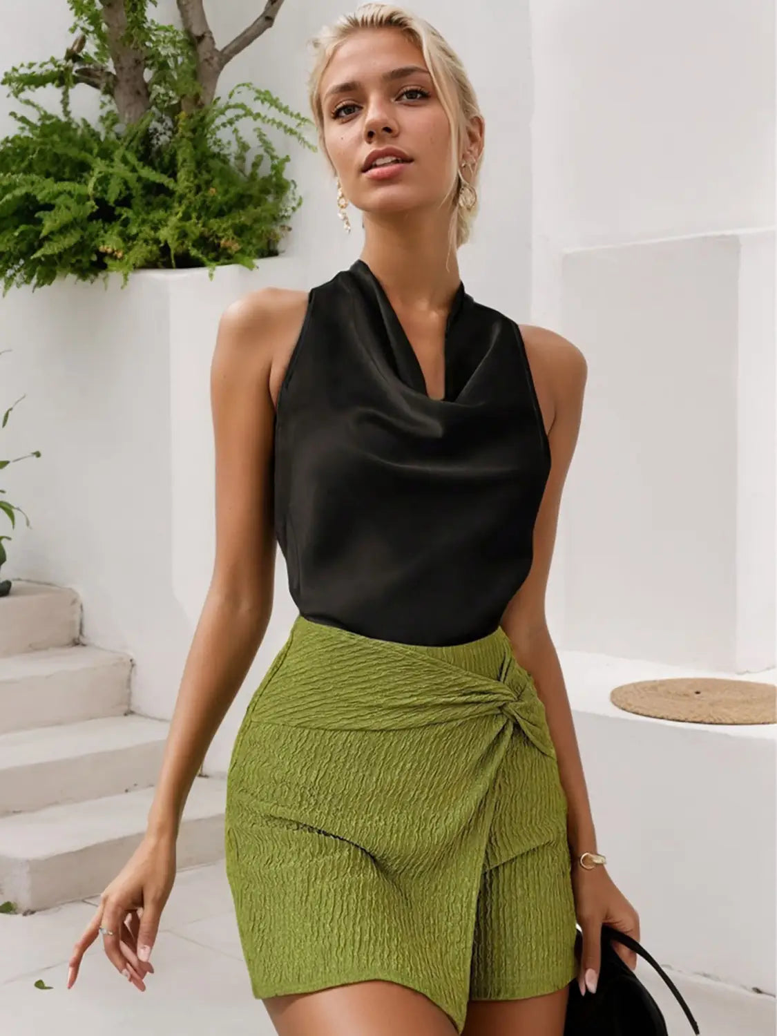 Grüner gemusterter Wickel-Minirock, kombiniert mit Satin-Cowl-Neck-Haltertop, das eine stilvolle Outfit-Kombination zur Schau stellt.